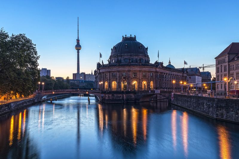 Das Bode-Museum an der Spitze der Museumsinsel im Morgengrauen, im Hintergrund der Fernsehturm, die Lichter spiegeln sich in der Spree