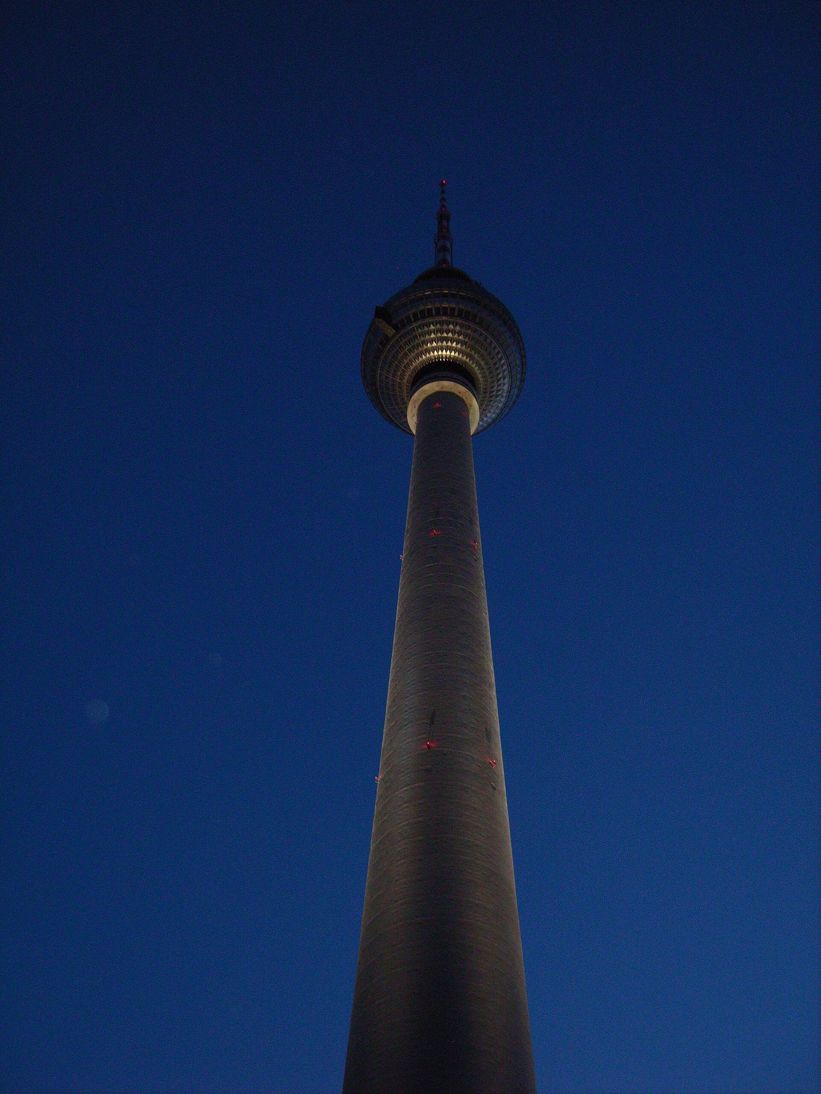 Steiler Blick von unten auf Schaft und Kugel des Fernsehturms vor tiefblauem Dämmerhimmel