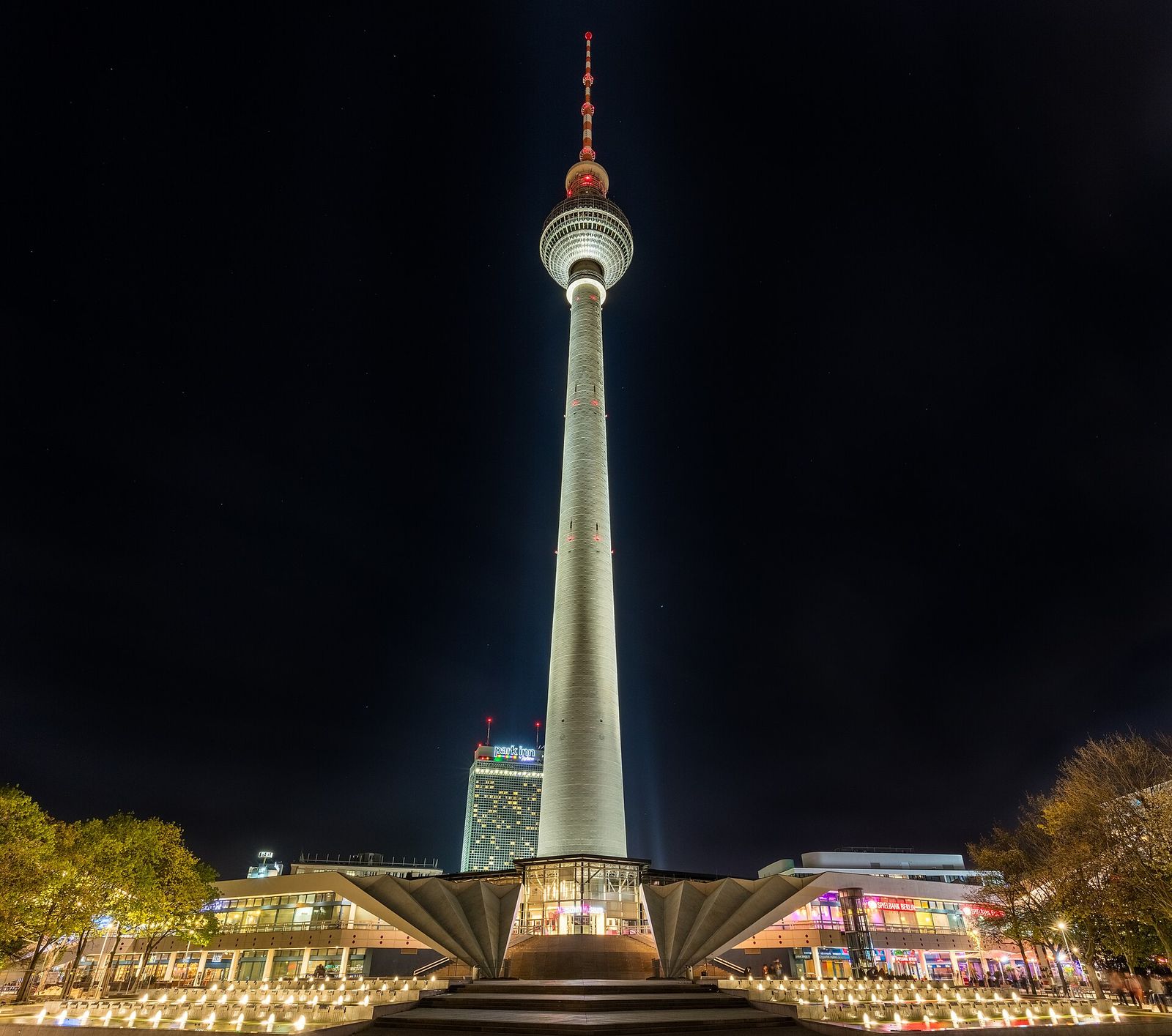 Der Fernsehturm bei Nacht, hell angestrahlt, mit dem Faltdach des Sockelbaus im Vordergrund