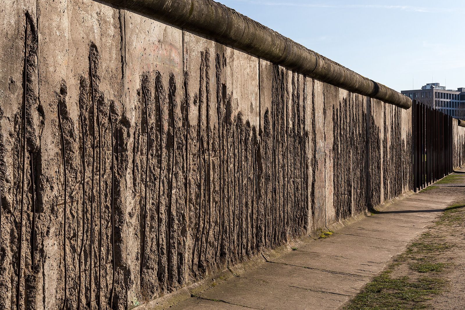 Teilstück der Berliner Mauer an der Bernauer Straße mit stark ausgebrochener, zerfurchter Betonoberfläche
