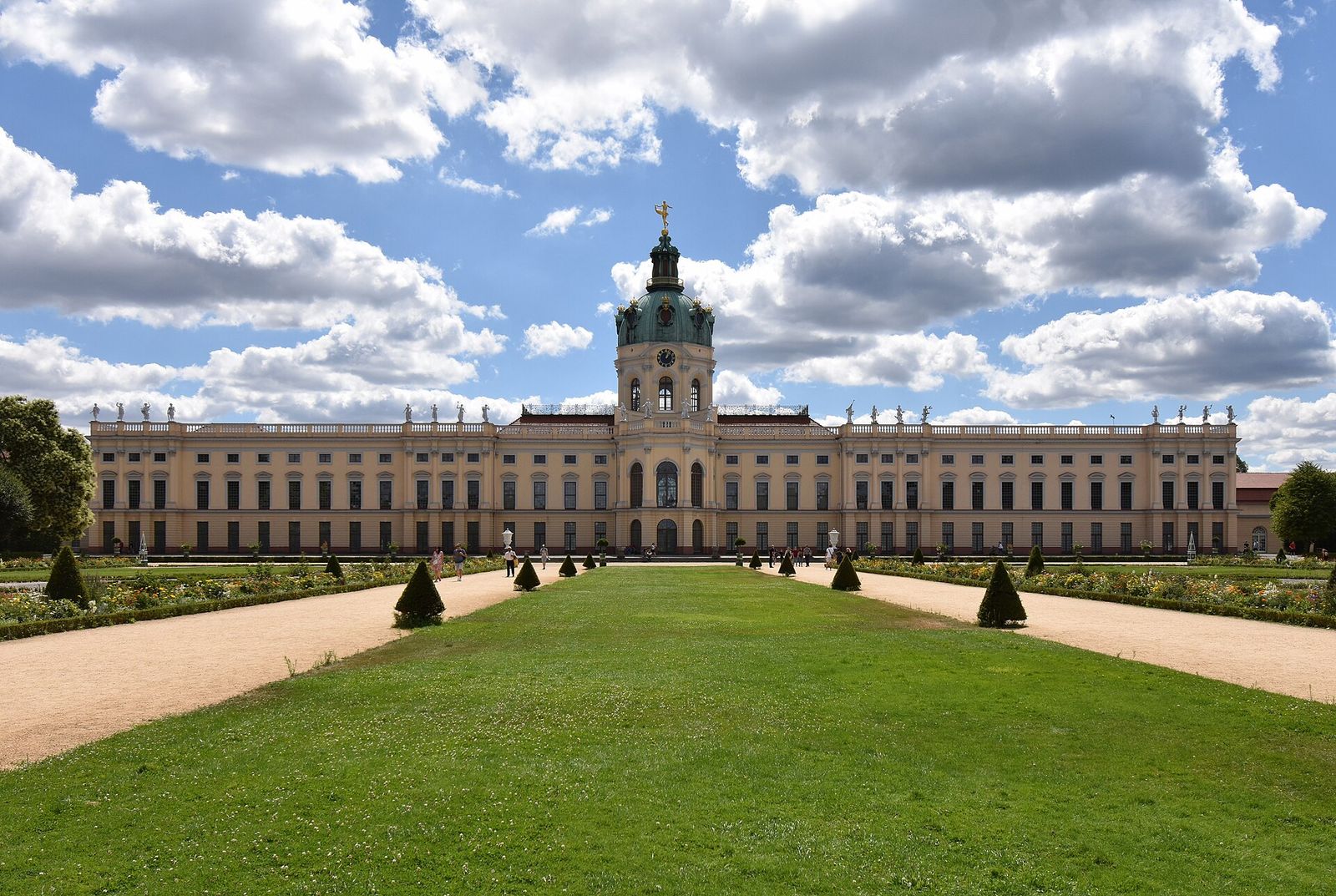Die Gartenfront von Schloss Charlottenburg mit Kuppelturm, davor Rasenachse und beschnittene Bäume des Barockgartens