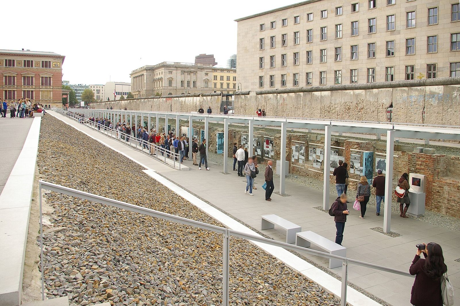 Ausgegrabene Kellerwände und Tafeln im Ausstellungsgraben der Topographie des Terrors, oberhalb ein erhaltenes Berliner Mauerstück an der Niederkirchnerstraße