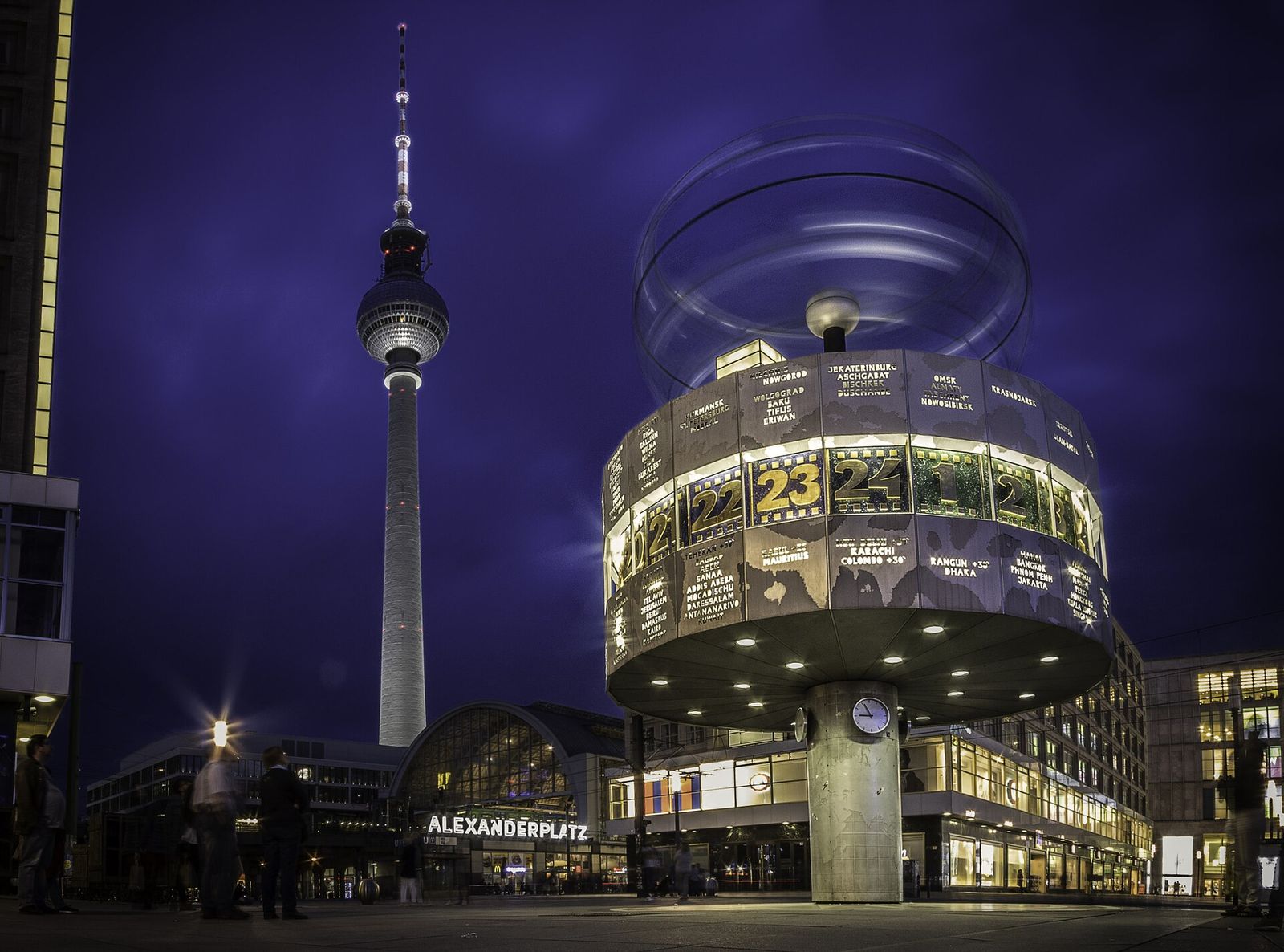Die abends beleuchtete Weltzeituhr auf dem Alexanderplatz, dahinter Fernsehturm und Bahnhof
